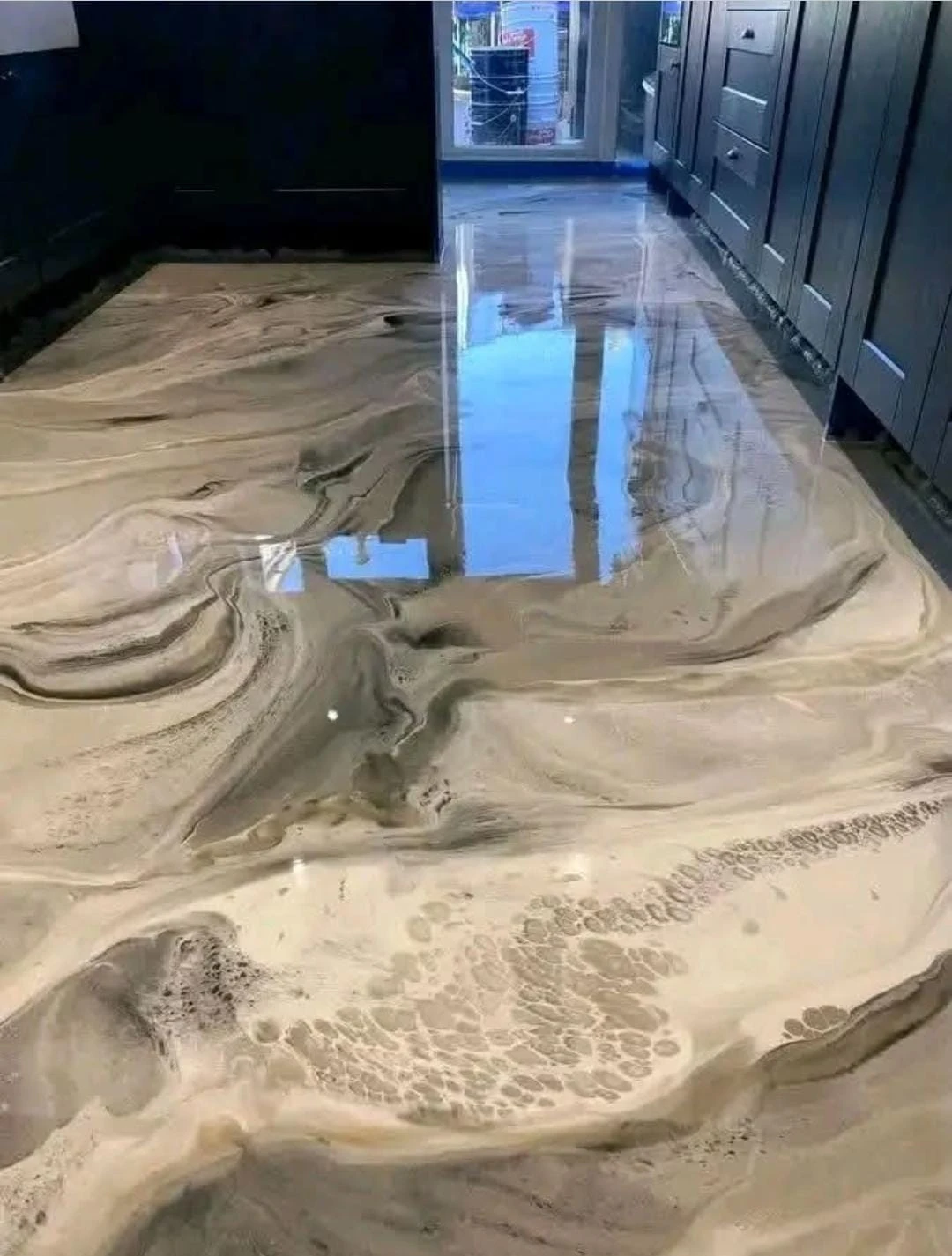 Dark cabinetry above a glossy patterned epoxy floor