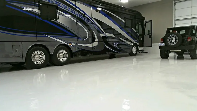 White epoxy floor in a large garage with an RV and Jeep