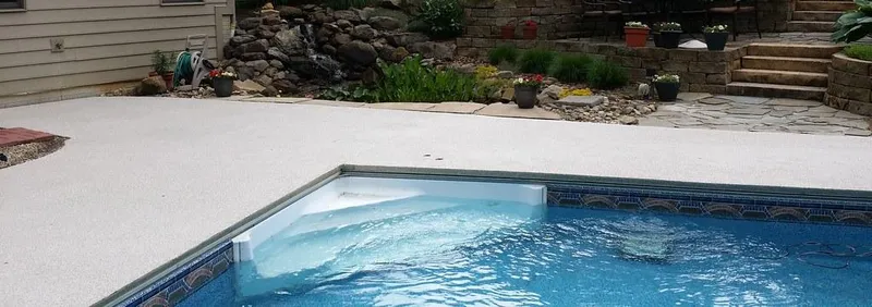 Light coating on a pool deck by a stone garden