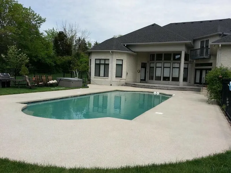 Light coated deck around a pool behind a house